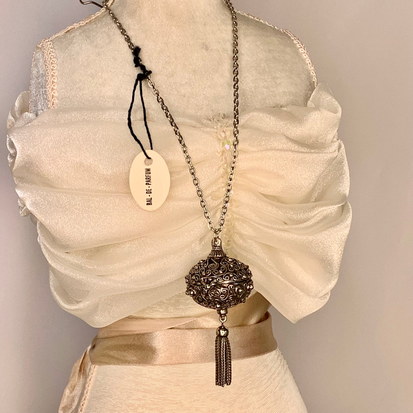 A vintage Florenza Bal-de-Parfum perfume necklace with tags.